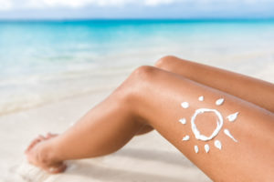 Sunscreen sun drawing lotion on suntan legs relaxing tanning on